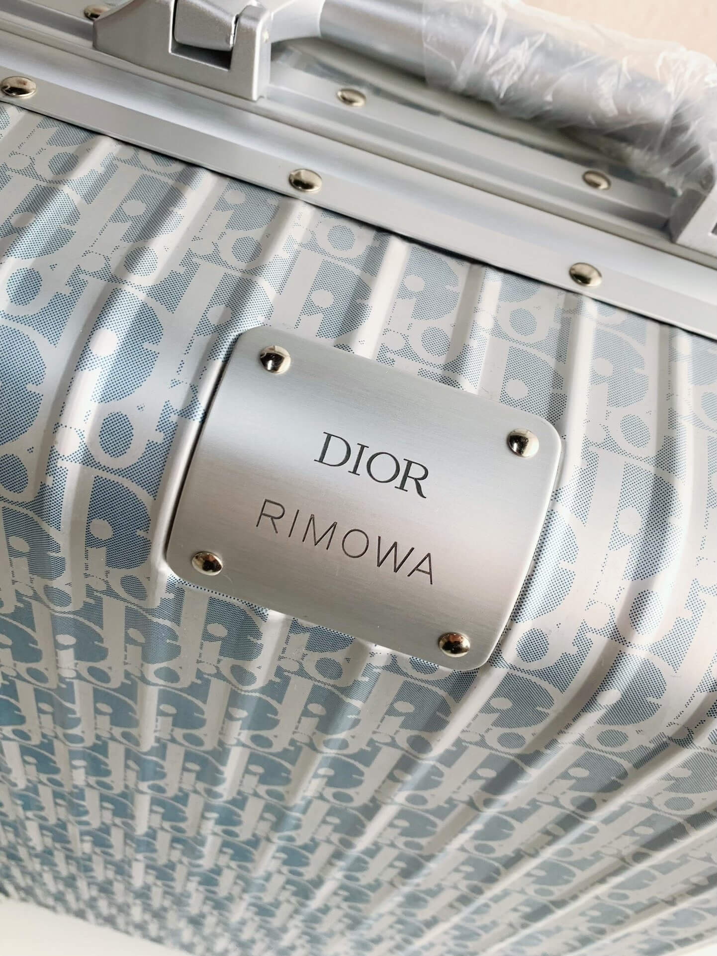 Close-up of a Dior Rimowa suitcase with a patterned design.