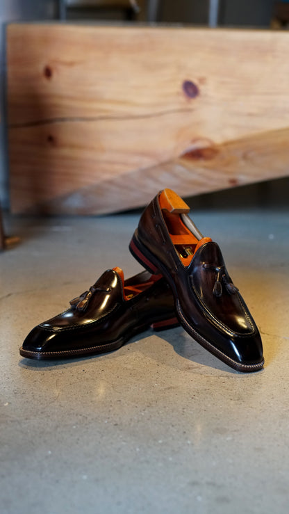 Hand-Made Dark Brown Leather Tassel Loafers – pair with shoe trees, resting on a concrete floor, emphasizing hand-painted patina and rubber grip inserts.