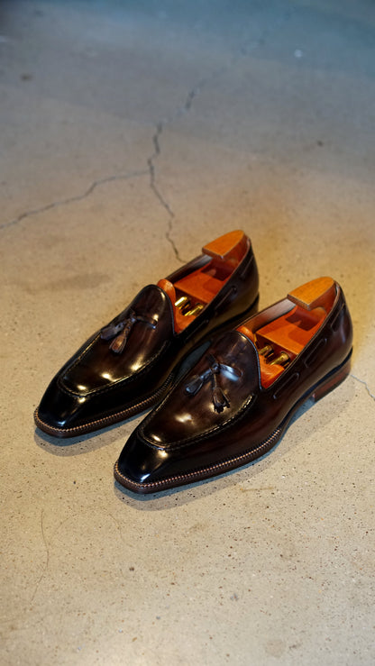 Hand-Made Dark Brown Leather Tassel Loafers – pair with shoe trees on a concrete surface, showcasing hand-painted patina and timeless charm.