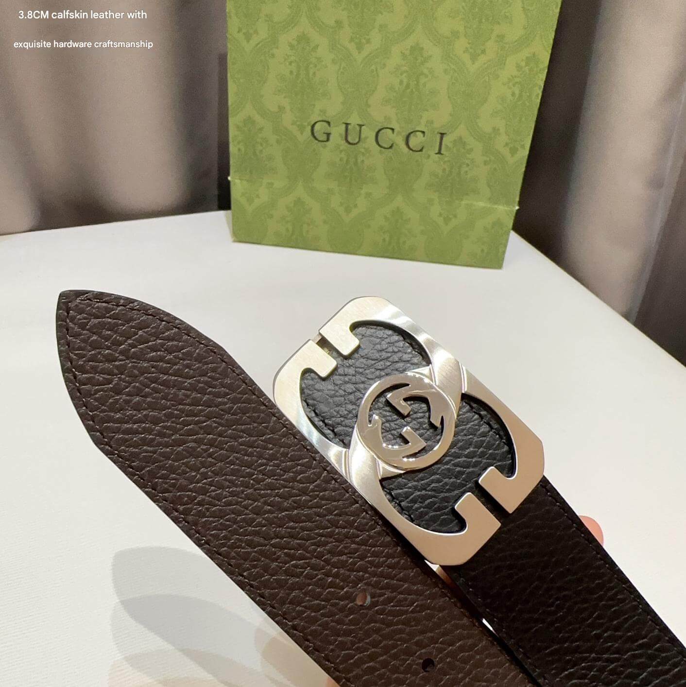 Brown leather belt with silver Gucci buckle on a white surface with a Gucci box in the background.