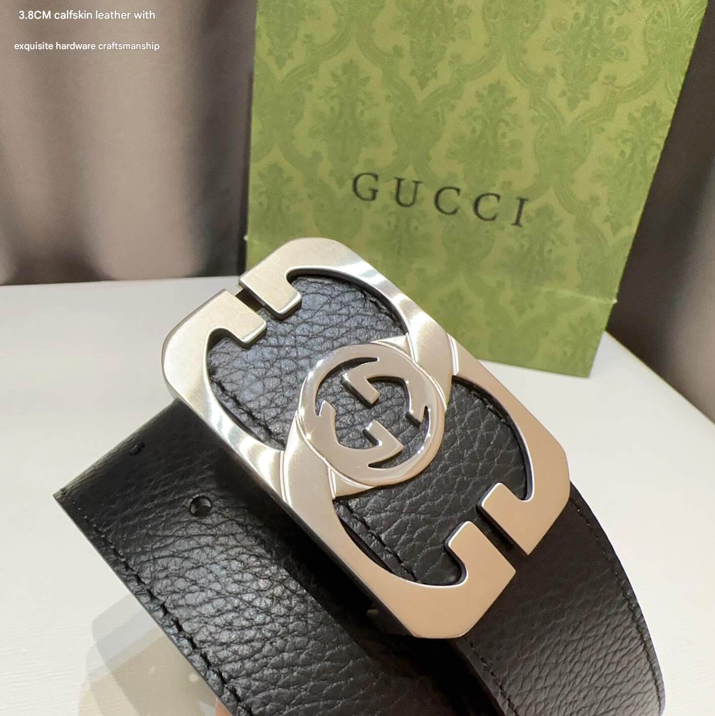 Gucci belt with gold buckle on a white surface with Gucci packaging in the background.