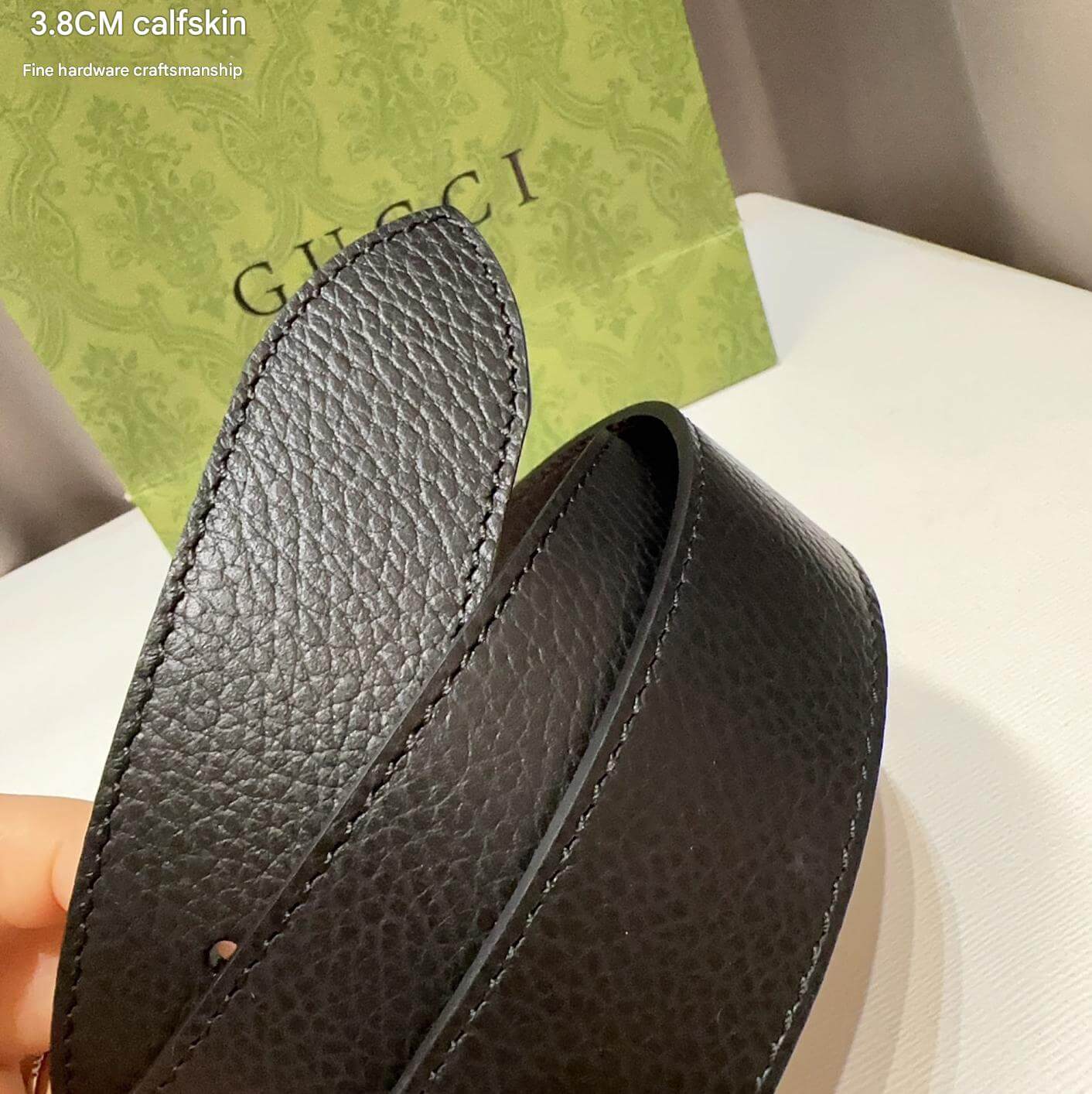 Close-up of a black leather belt with 'Gucci' branding in the background.