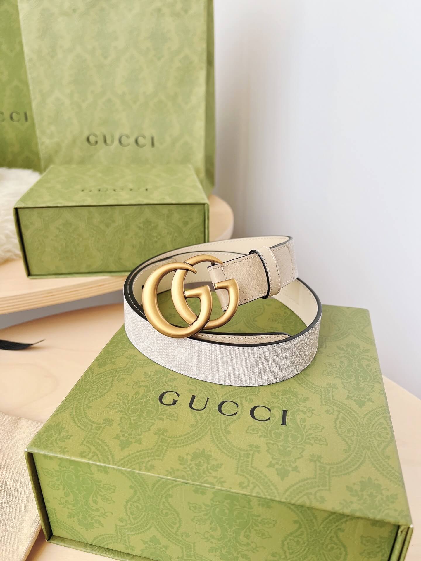 Gucci belt on a Gucci box with green packaging in the background