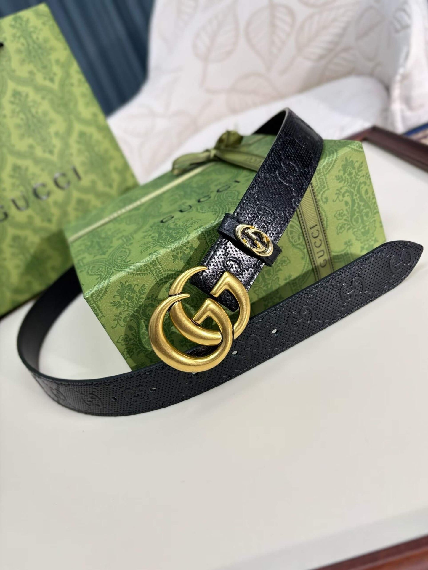 Black Gucci belt with gold logo on a green box