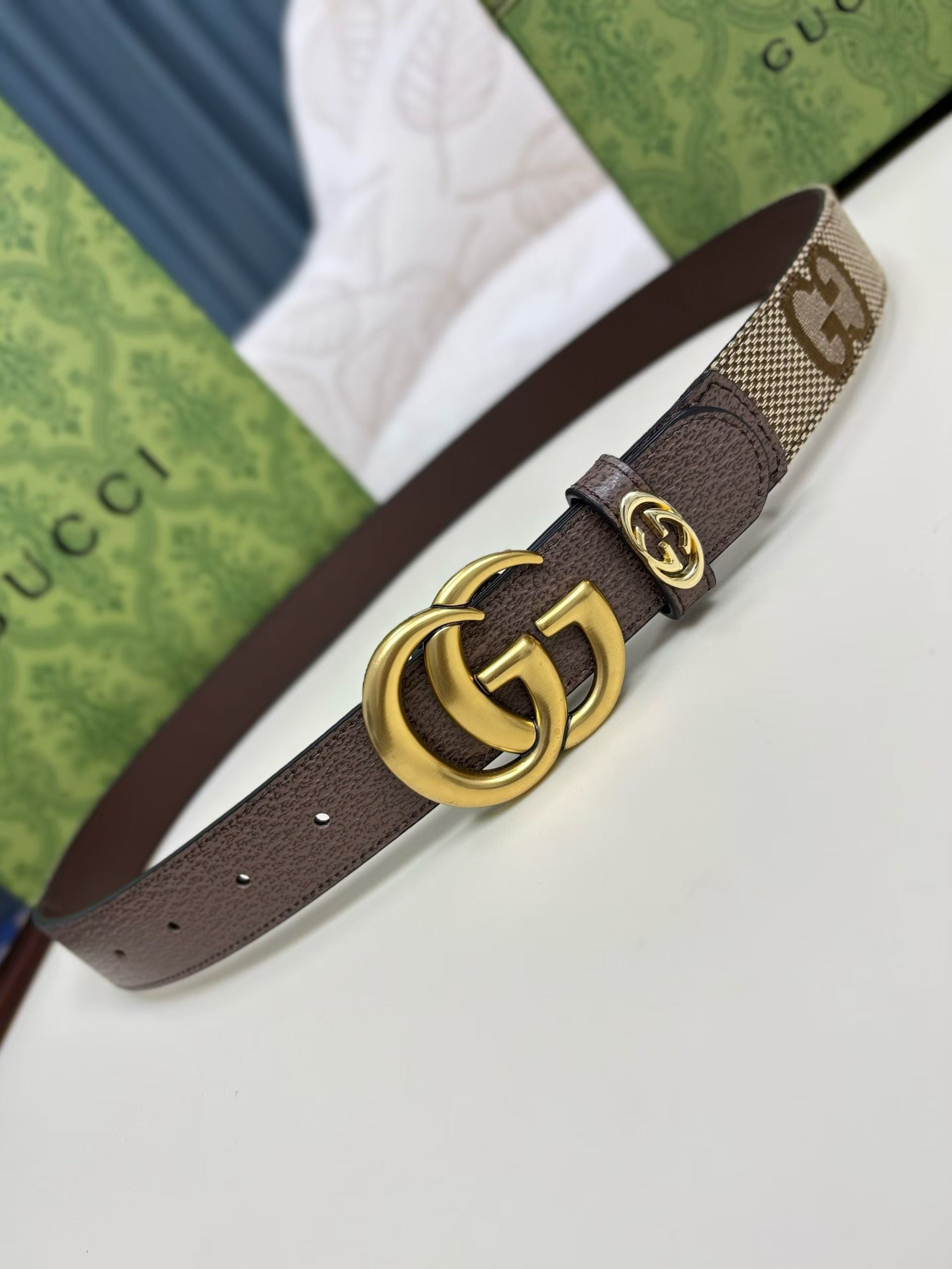Brown Gucci belt with gold buckle on a white surface