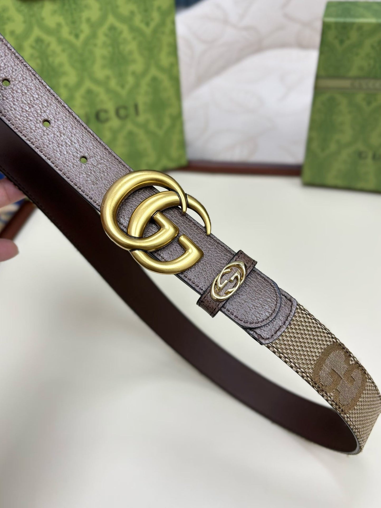 Brown leather belt with gold Gucci logo buckle on a white background