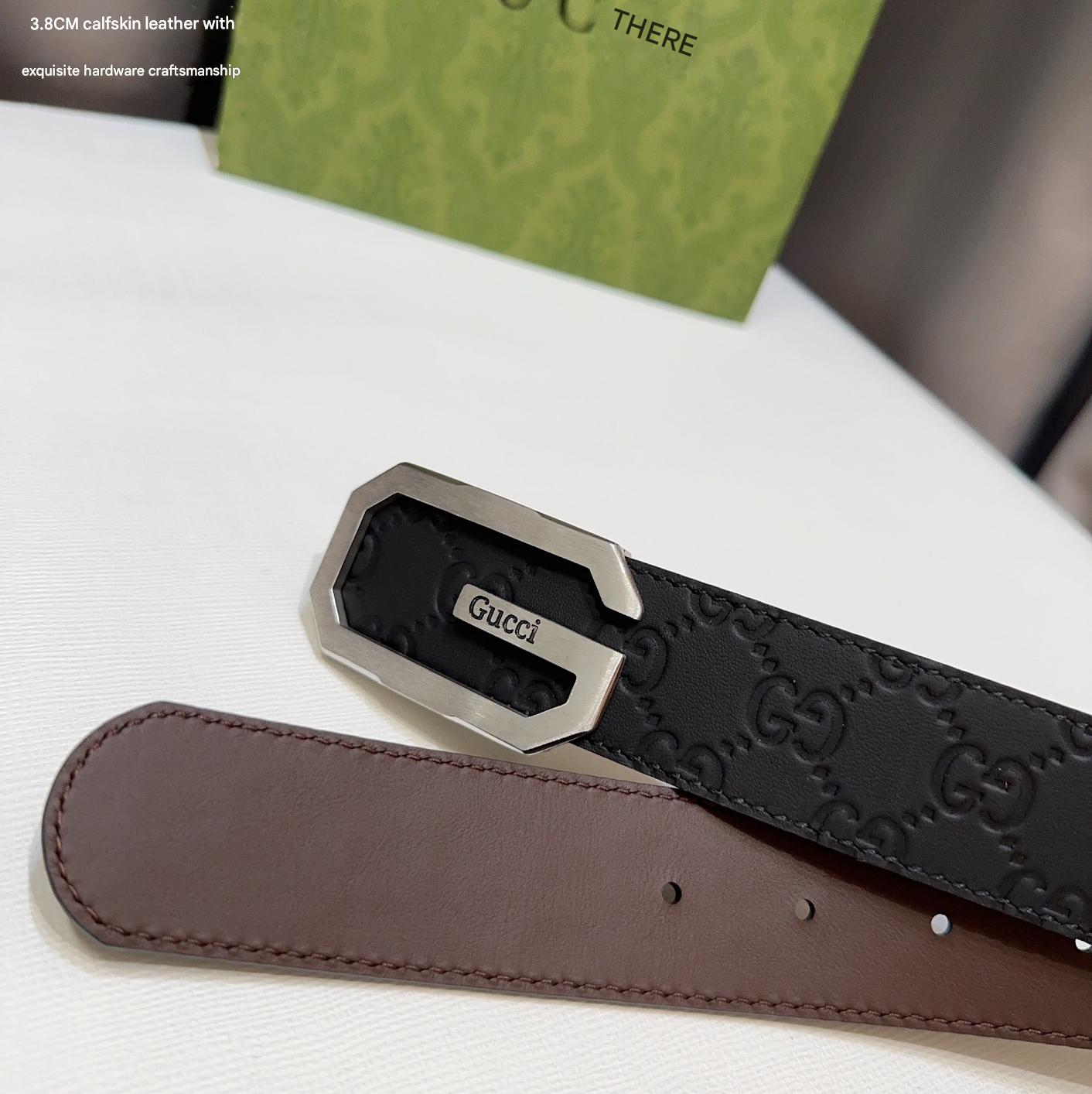 Brown leather belt with silver Gucci buckle on a white surface