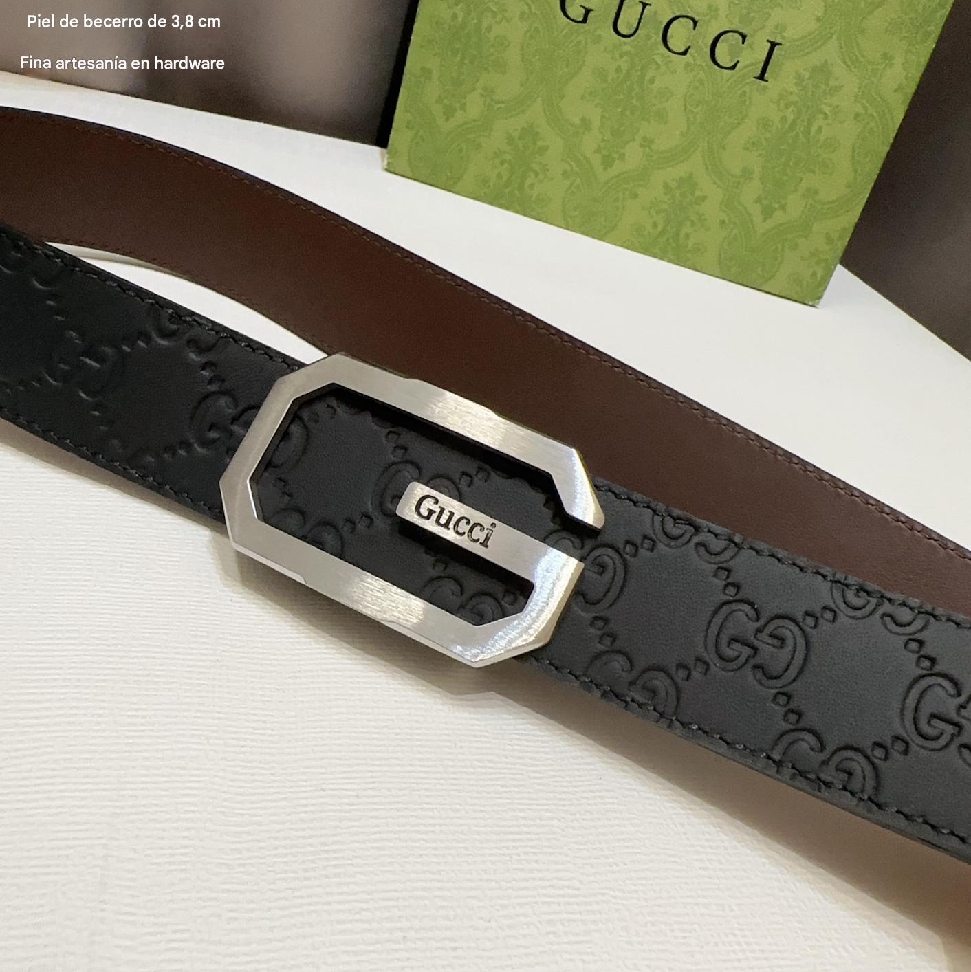 Gucci belt with silver buckle on a white surface, with a Gucci card in the background.