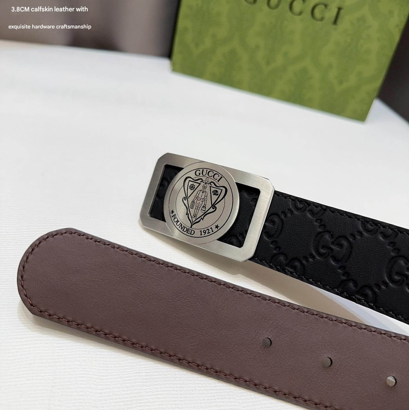 Black Gucci belt with silver buckle on a white surface