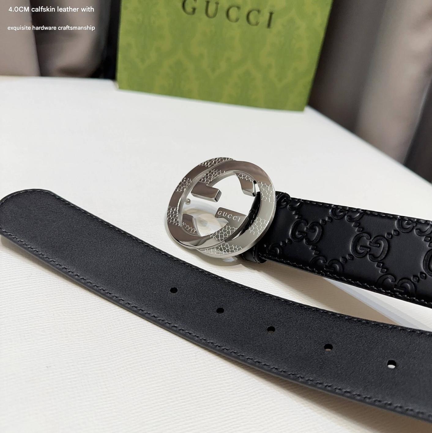 Black Gucci belt with silver buckle on a white surface, with a Gucci box in the background.