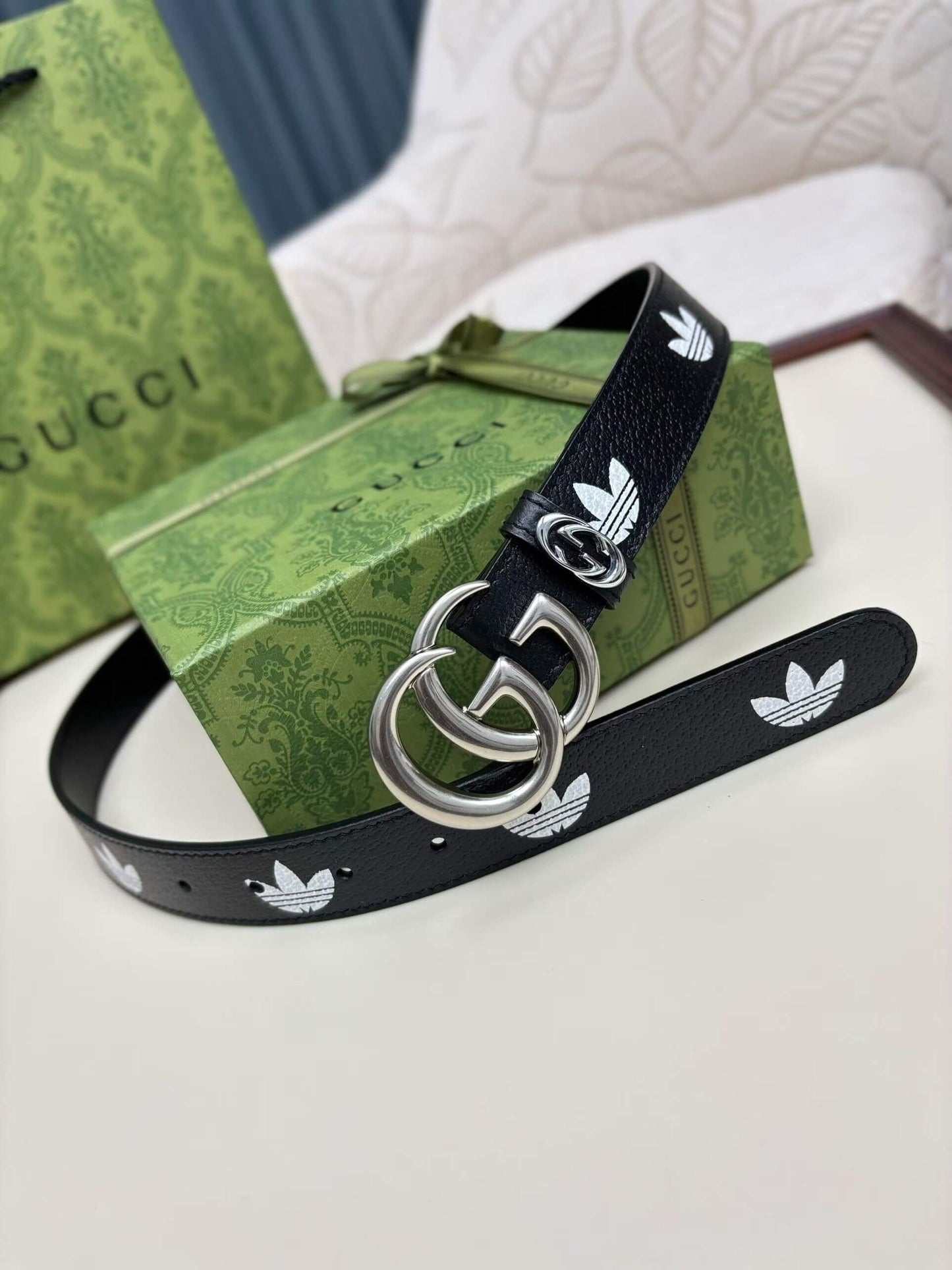 Black belt with white logo on a green Gucci box