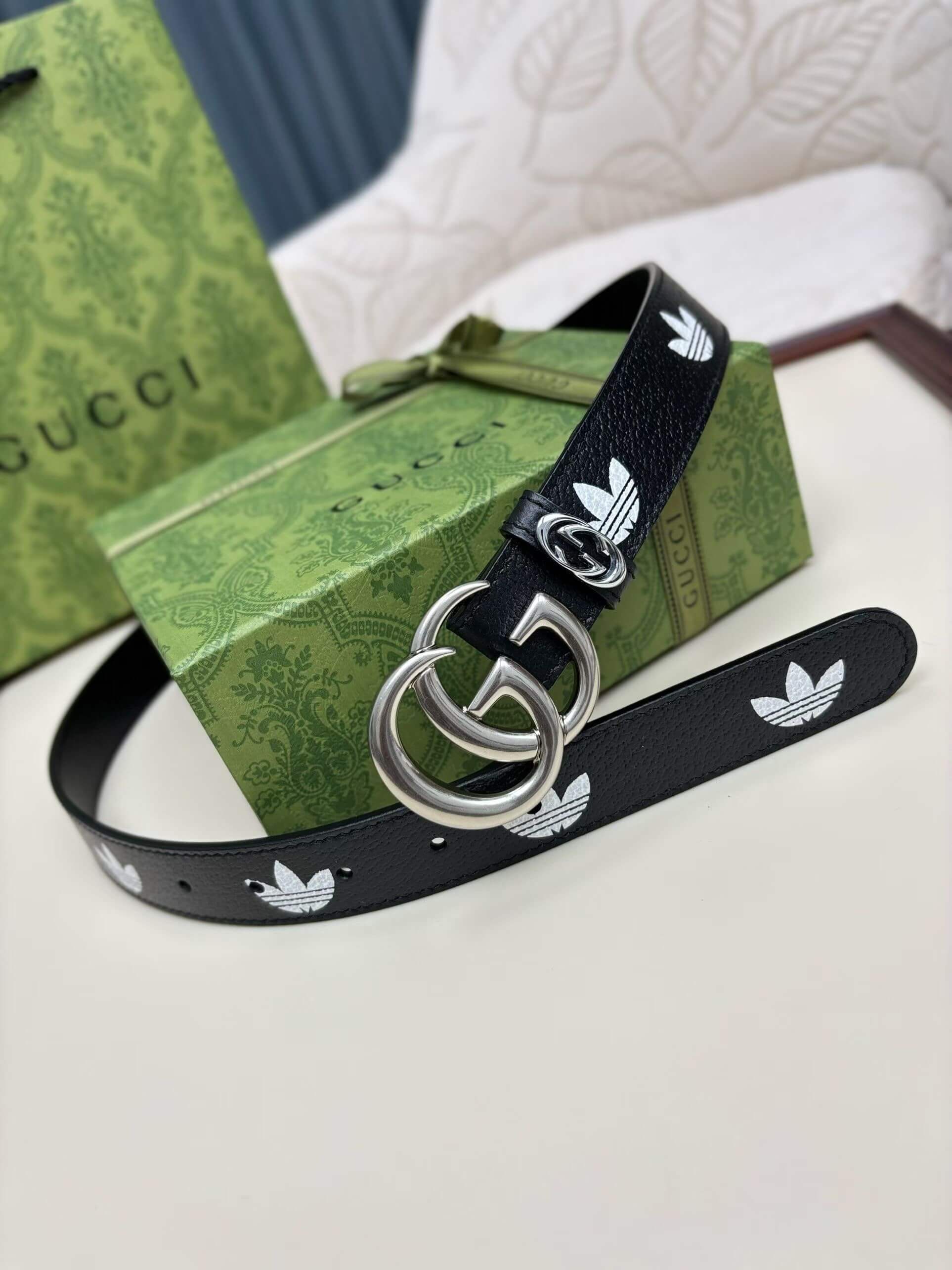 Black belt with white logo on a green Gucci box