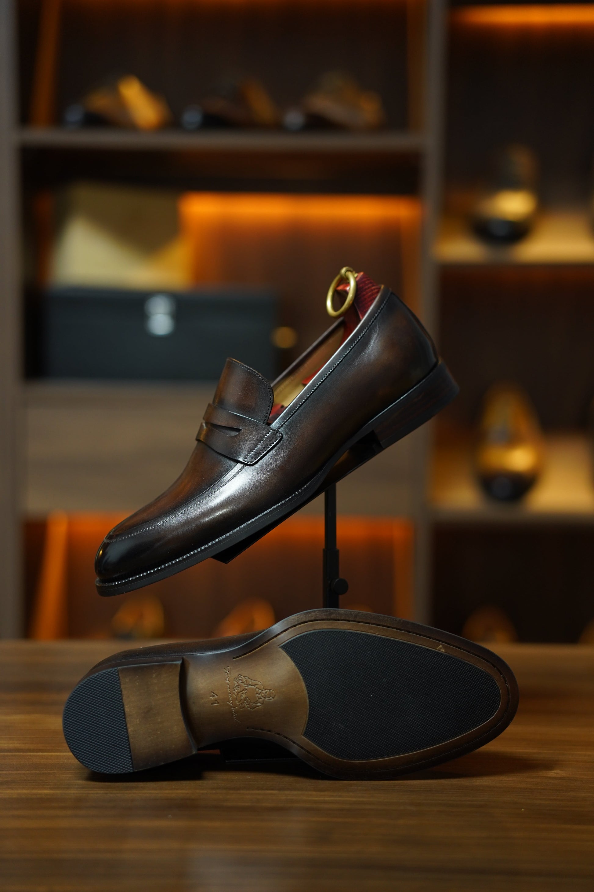 Hand-Burnished Brown Leather Penny Loafers – side view with one shoe upright, highlighting the hand-polished finish, signature stitched saddle strap, and rubber insert.