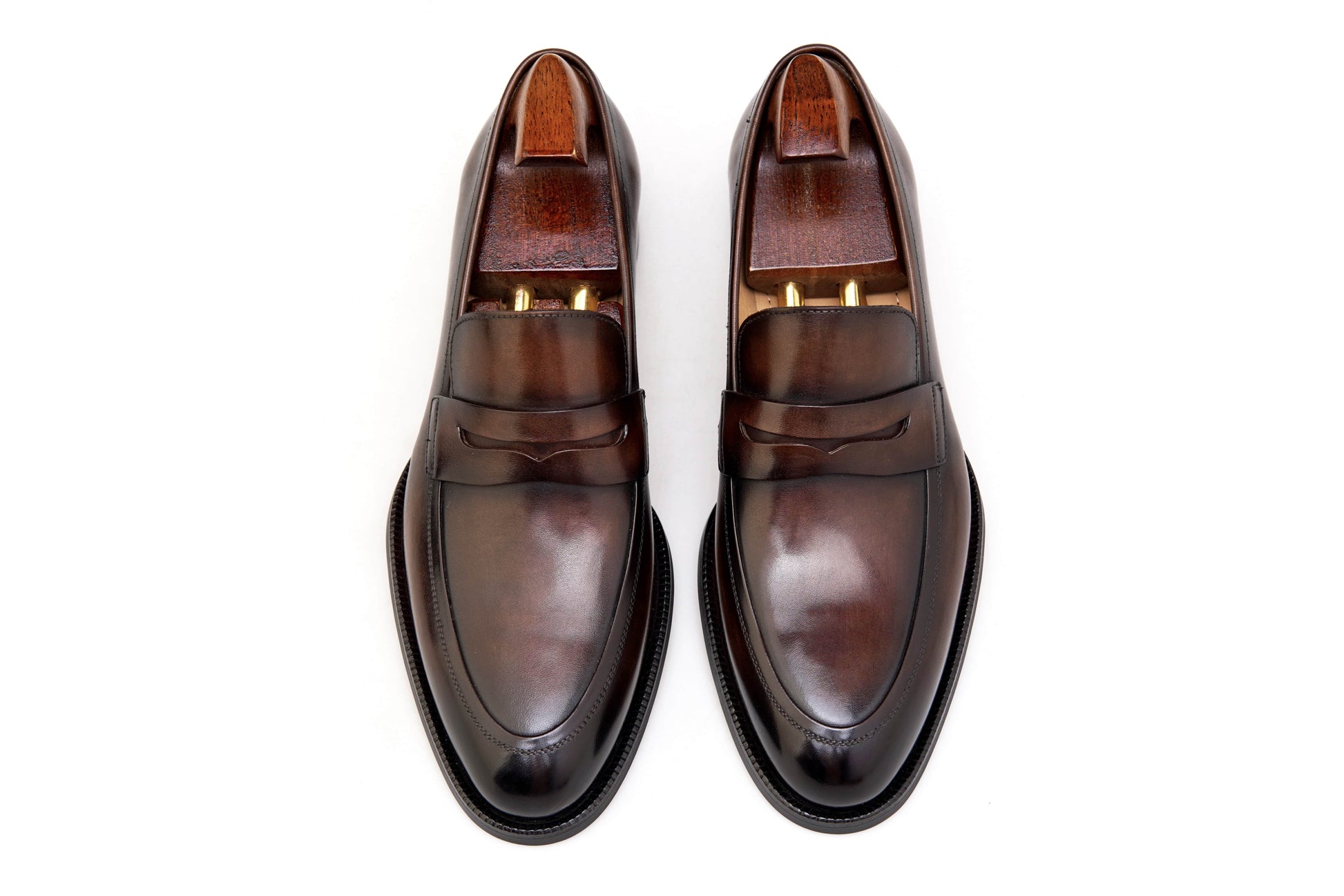 Hand-Burnished Brown Leather Penny Loafers – pair with shoe trees, top-down view, emphasizing the rich hand-polished leather and classic penny loafer design.