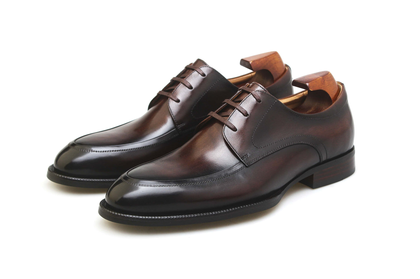 A pair of HolloShoe Hand-Burnished Chestnut Split-Toe Derby shoes with shoe trees, angled view, highlighting the hand-burnished chestnut leather and apron toe.