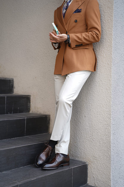  A man wearing HolloShoe Hand-Burnished Chestnut Split-Toe Derby shoes with a brown blazer and light trousers, standing on steps.