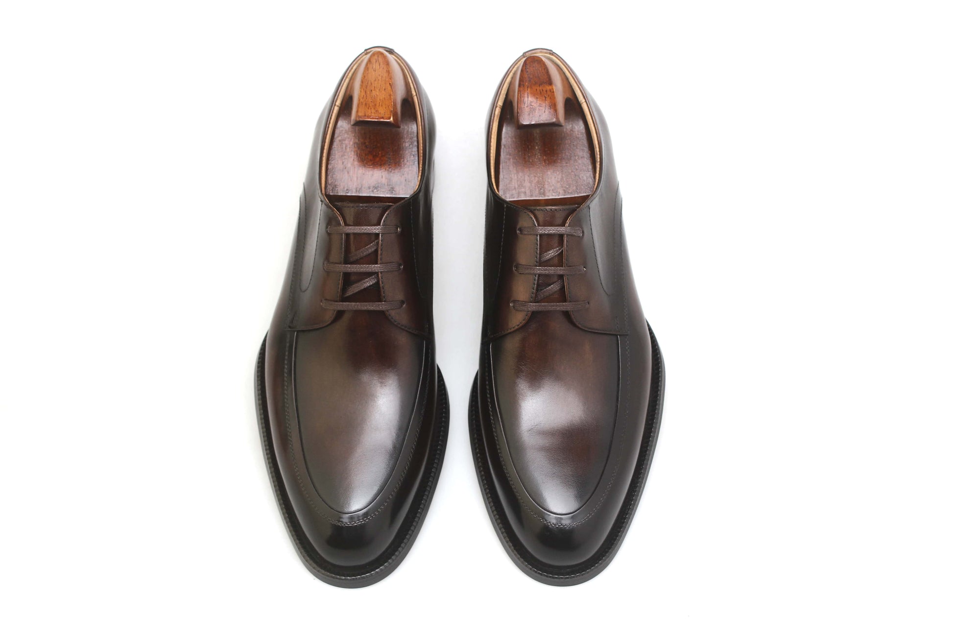 Overhead view of a pair of HolloShoe Hand-Burnished Chestnut Split-Toe Derby shoes with shoe trees, showcasing their rich burnished chestnut leather.