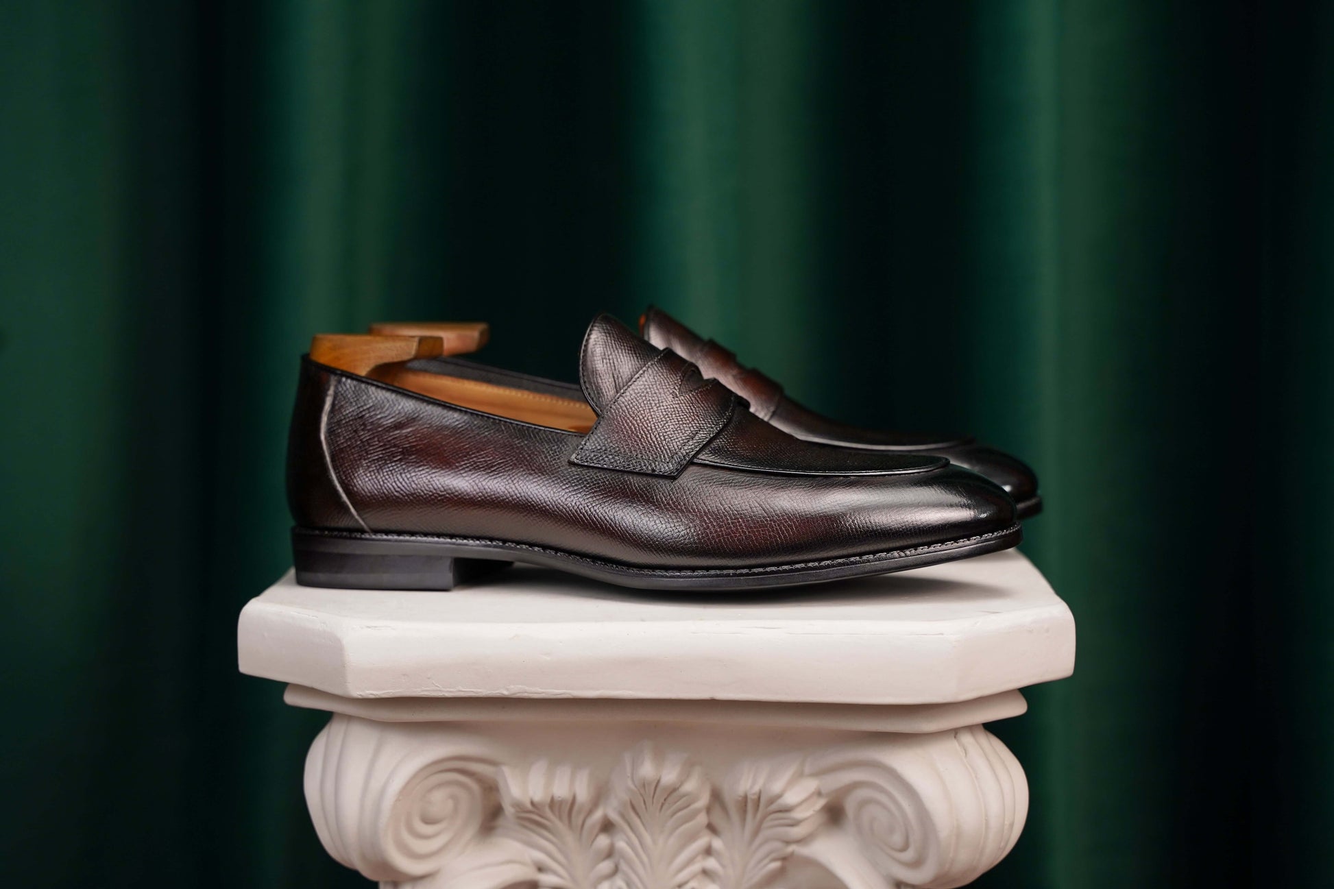 Hand-Finished Espresso Brown Leather Penny Loafers – side view on a white classical pedestal, showcasing rich hand-finished brown leather and subtle heel support.