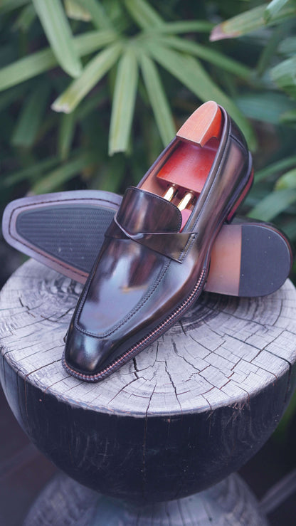 Hand-Painted Dark Brown Leather Penny Loafers – pair on a wooden table in a box, highlighting hand-painted patina and sleek chisel toe.