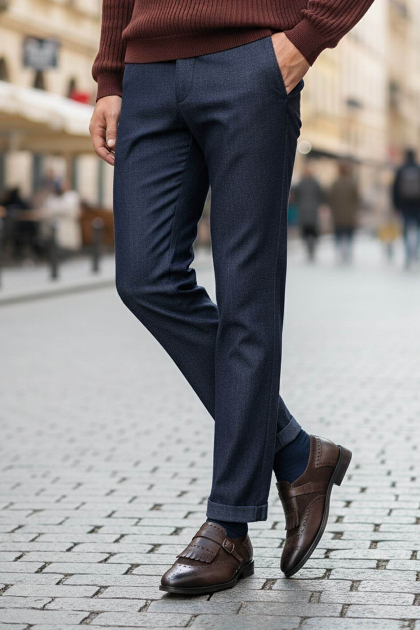 Person wearing navy pants and brown shoes on a blurred street background