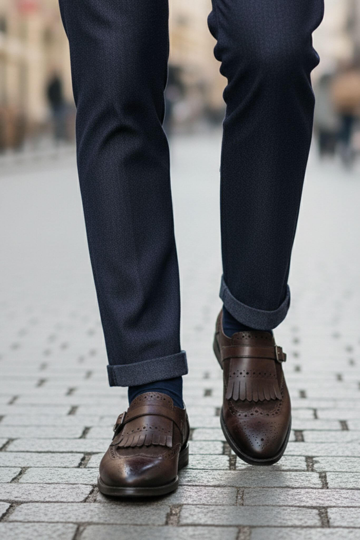 Brown loafers and navy pants on a blurred street background