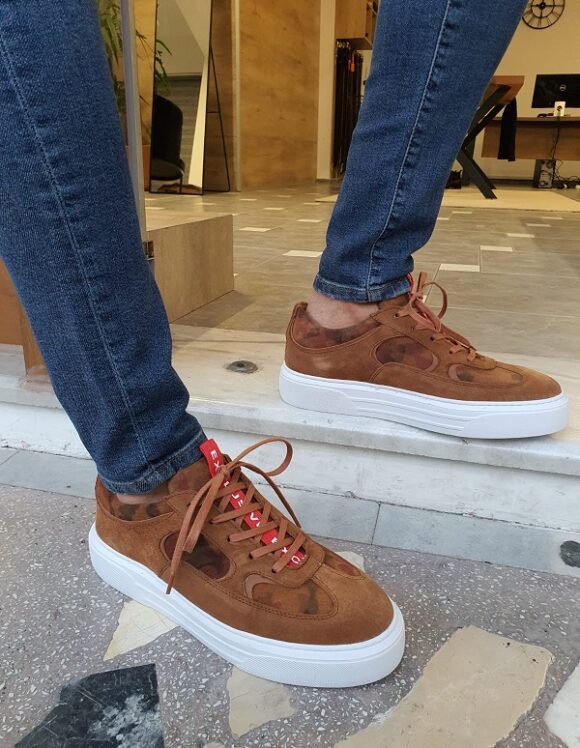 Sophisticated Handcrafted Brown Suede Sneakers – worn by a man in dark denim jeans, standing, showcasing a modern mid-top design and a thick white sole. 
