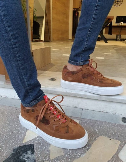 Sophisticated Handcrafted Brown Suede Sneakers – worn by a man in dark denim jeans, standing, showcasing a modern mid-top design and a thick white sole. 
