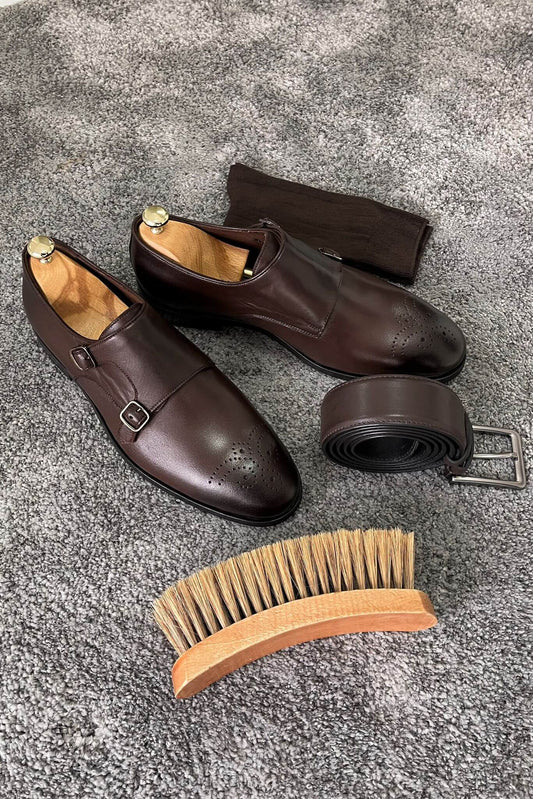 Brown leather shoes with a belt and brush on a textured surface