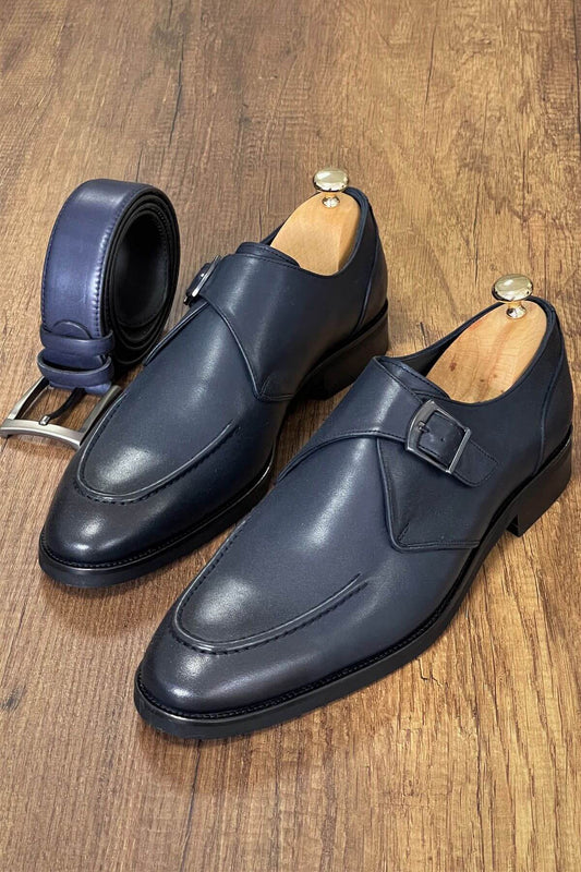 Pair of navy blue dress shoes with a belt on a wooden surface
