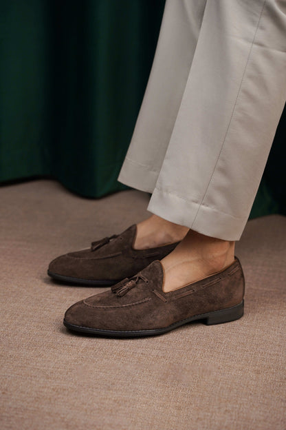 Handcrafted Umber Dark Brown Tassel Suede Loafers – worn by a man in light trousers, showcasing refined minimalism and rich dark brown suede for everyday ease.Handcrafted Umber Dark Brown Tassel Suede Loafers – worn by a man in light trousers, showcasing refined minimalism and rich dark brown suede for everyday ease.