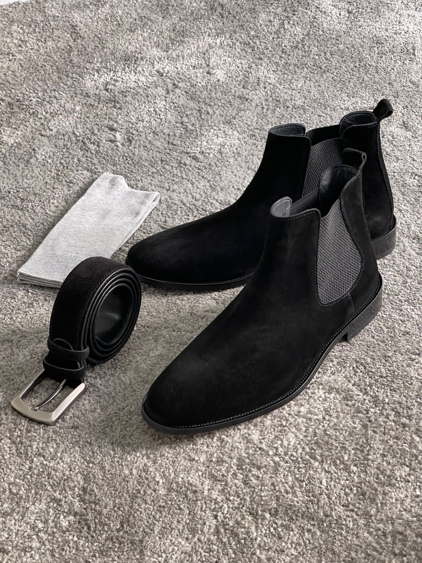 Handmade Classic Black Suede Chelsea Boots – a side view of a pair of black suede boots next to a belt and socks.