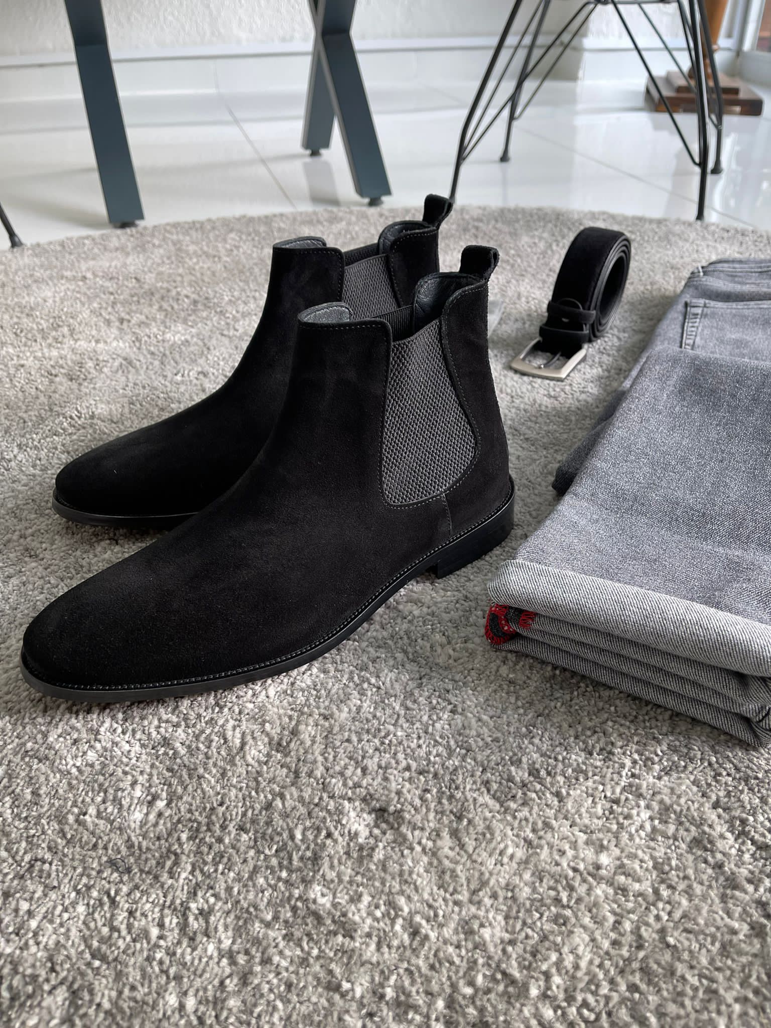 Handmade Classic Black Suede Chelsea Boots – a side view of the boots next to rolled-up gray pants, a belt, and socks.