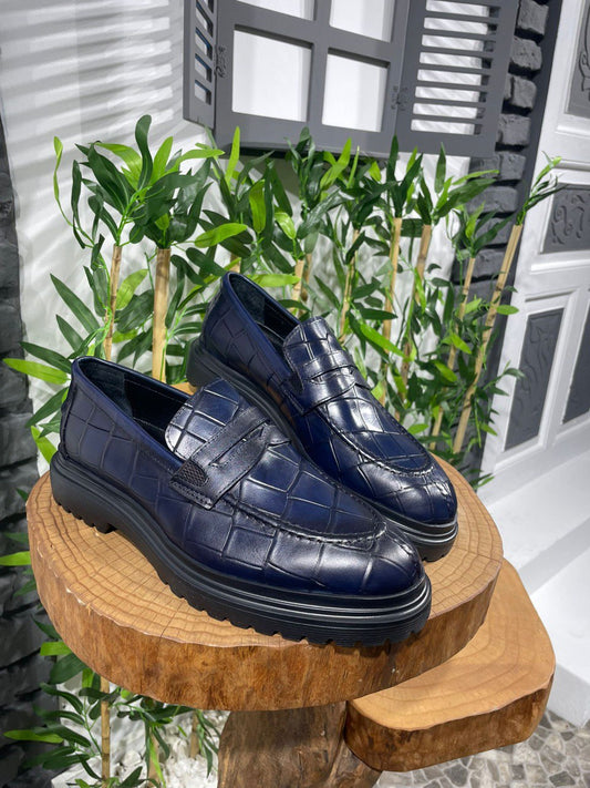 Handmade Navy Blue Crocodile-Embossed Leather Penny Loafers – luxurious textured leather, displayed on a wooden stand with a green background for a sophisticated and modern look.