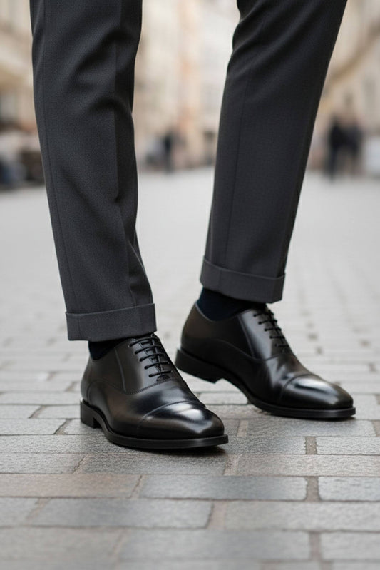 Black dress shoes and gray pants on a blurred street background