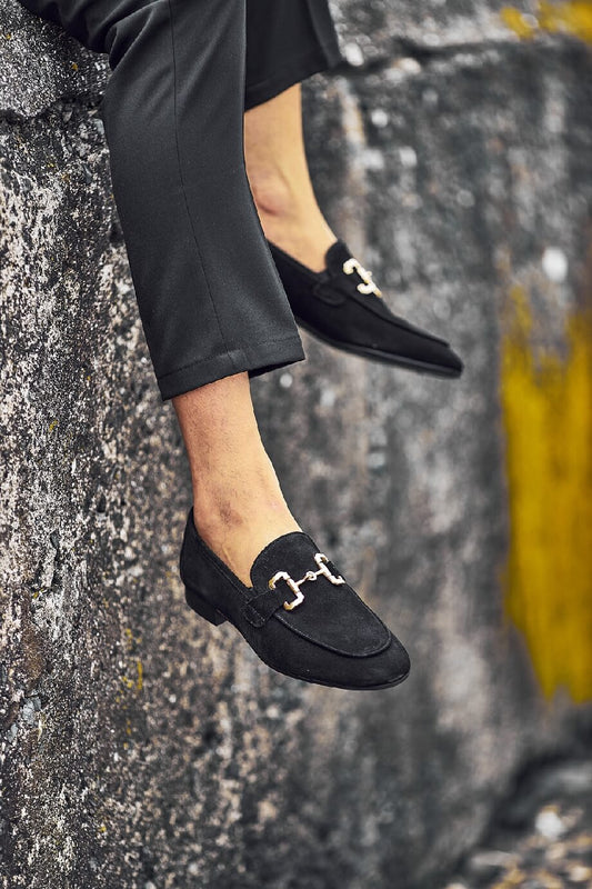 HolloShoe Black Suede Horsebit Loafers for Business & Casual Wear – elegant shoes, worn with black trousers, with one foot lifted against a rocky background, highlighting timeless style and comfort.