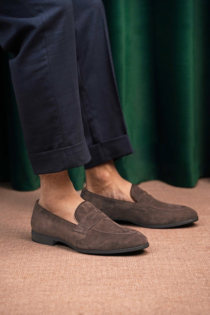 Earth Brown Suede Penny Loafers – worn by a man in cuffed navy trousers, showcasing refined minimalism and soft brown suede for everyday ease.