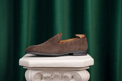 HolloShoe Earth Brown Suede Penny Loafer – side view with shoe tree, resting on a classical pedestal, highlighting refined finish and long-wearing build.