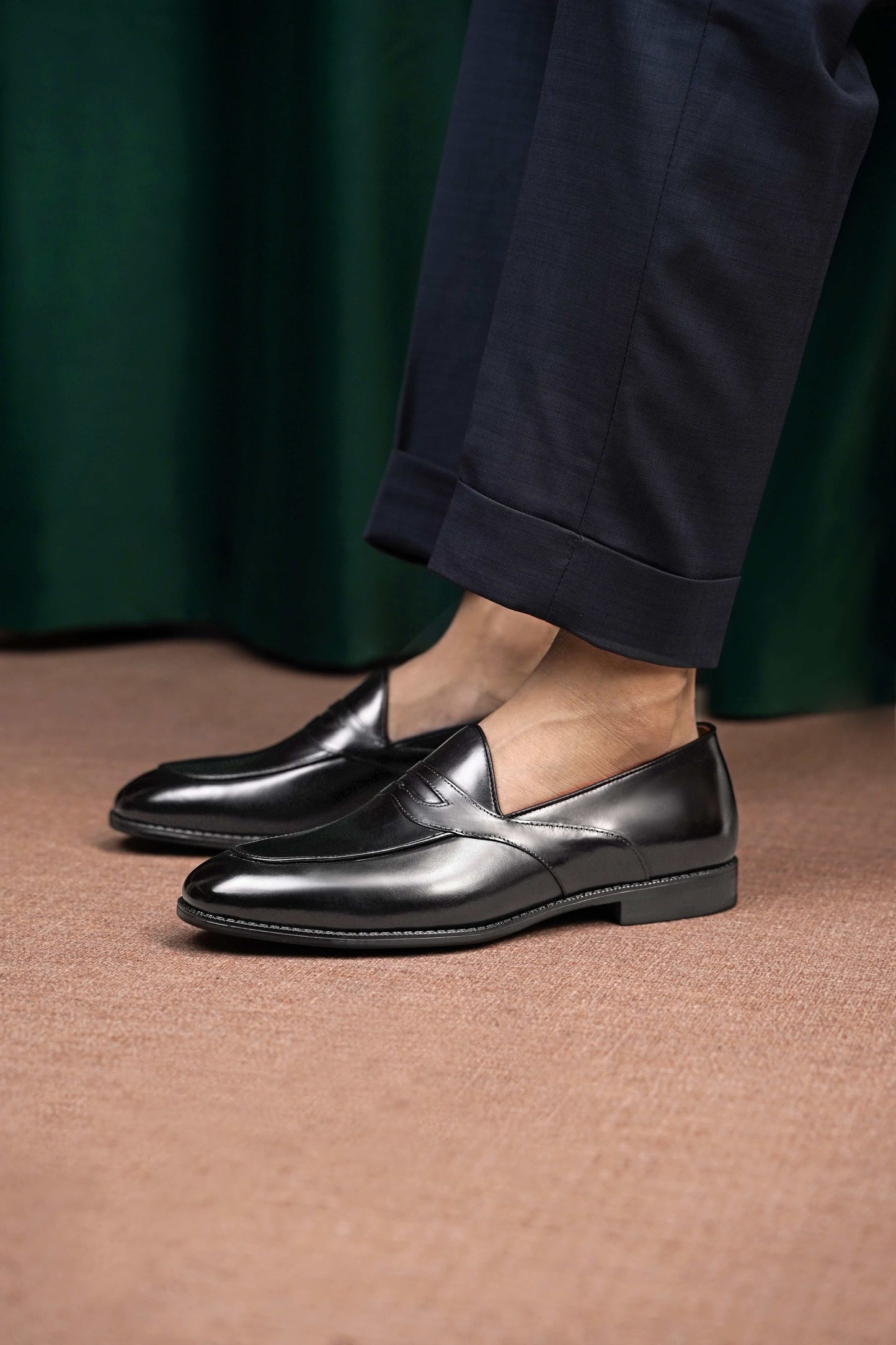 HolloShoe Handmade Black Leather Penny Loafers – worn by a man in cuffed navy trousers, standing on a patterned rug, highlighting sleek black leather for refined styling.