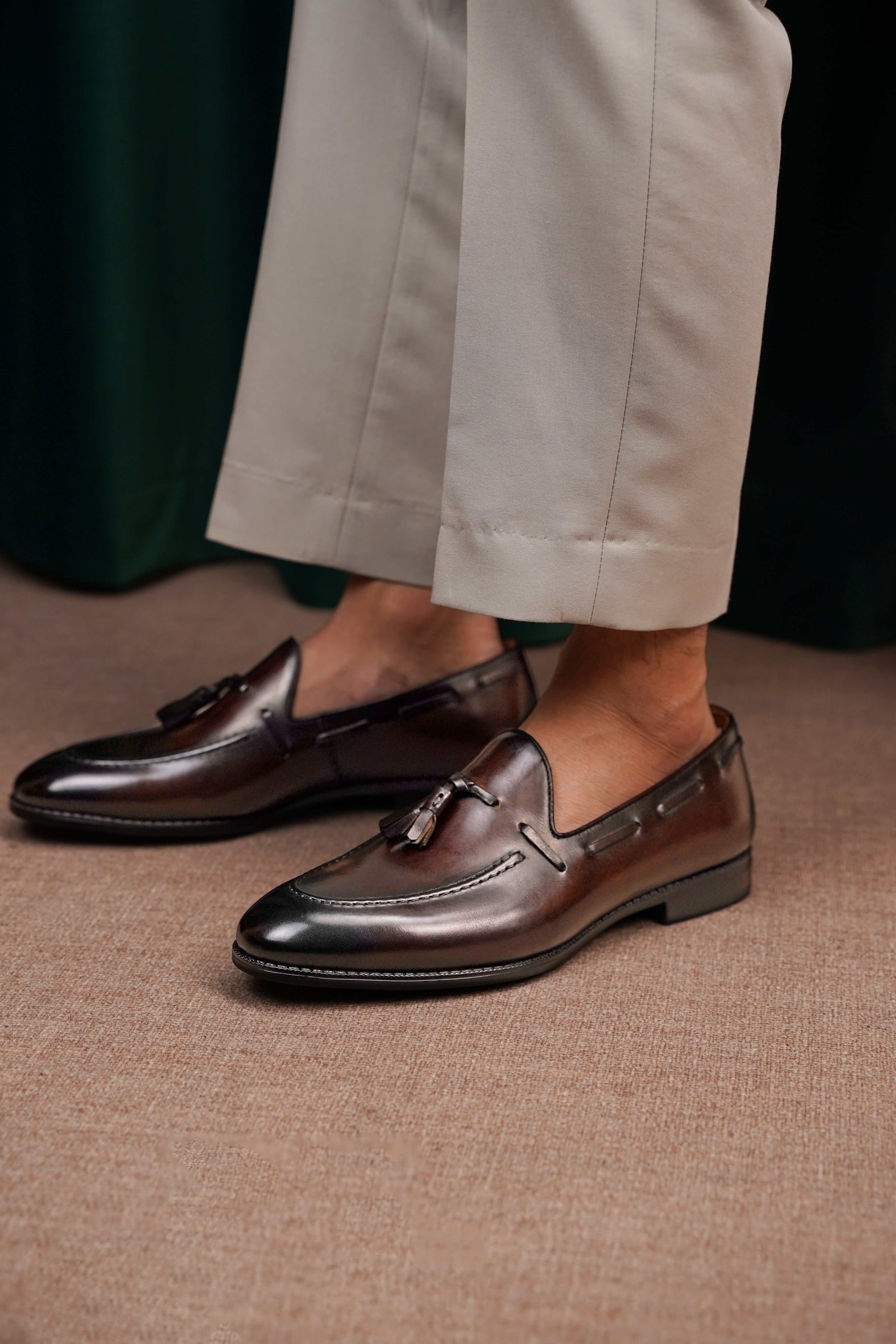HolloShoe Handmade Chestnut Brown Patina Tassel Loafers – worn by a man in light trousers, standing on a patterned rug, emphasizing rich brown patina and signature tassels.