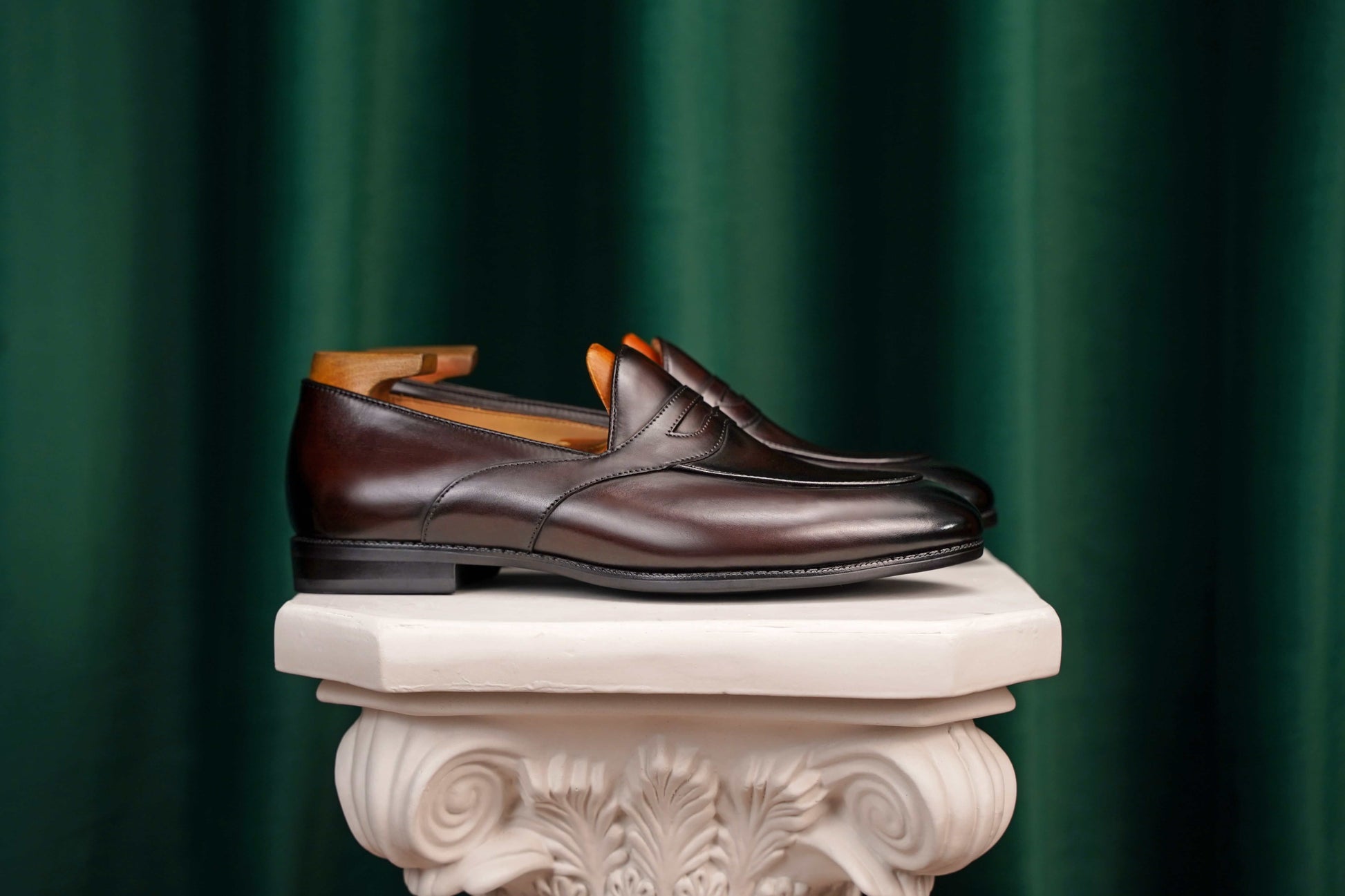 HolloShoe Handmade Dark Tan Leather Penny Loafers – pair with shoe trees, resting on a white classical pedestal, highlighting rich dark tan leather.