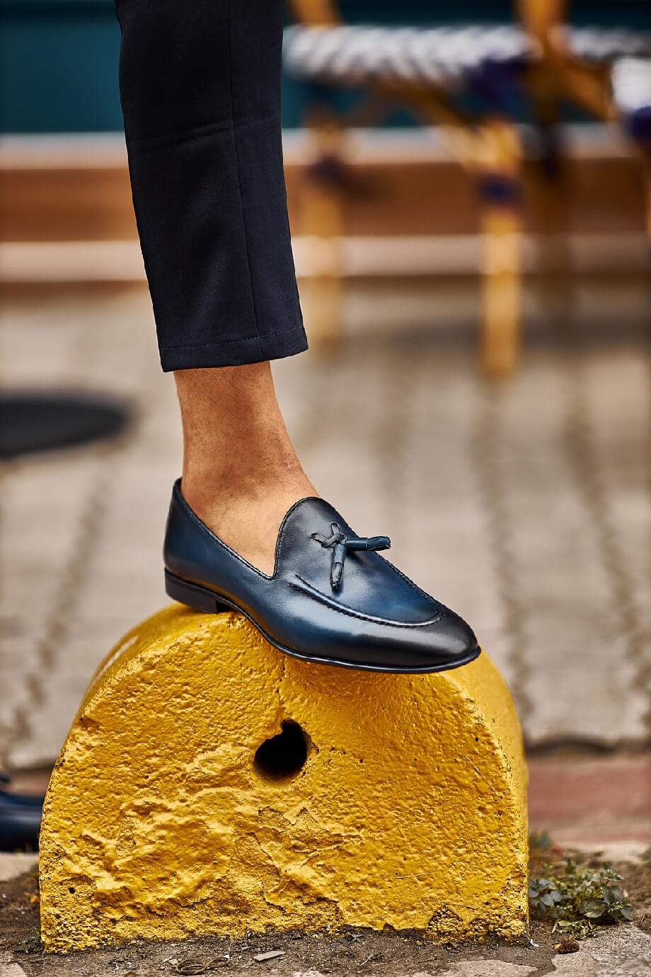 HolloShoe Navy Blue Tassel Loafers - Sophisticated Leather Footwear – worn by a man in dark trousers, standing on a yellow concrete block, highlighting a refined look.