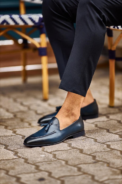 HolloShoe Navy Blue Tassel Loafers - Sophisticated Leather Footwear – worn by a man in cuffed black trousers, sitting outdoors, showcasing a sophisticated and sharp look.