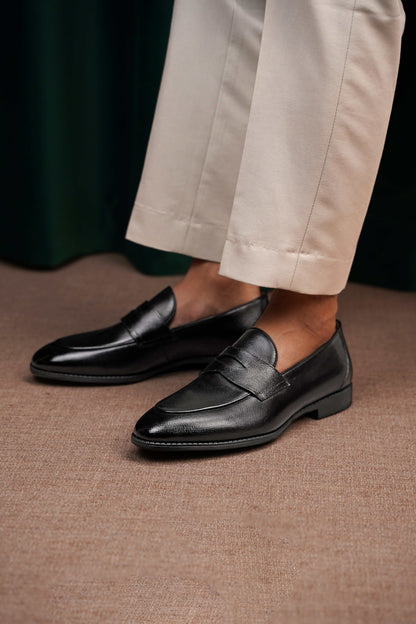 HolloShoe Black Penny Loafers – pair on a white pedestal, showcasing polished black textured leather and classic design with shoe trees.
