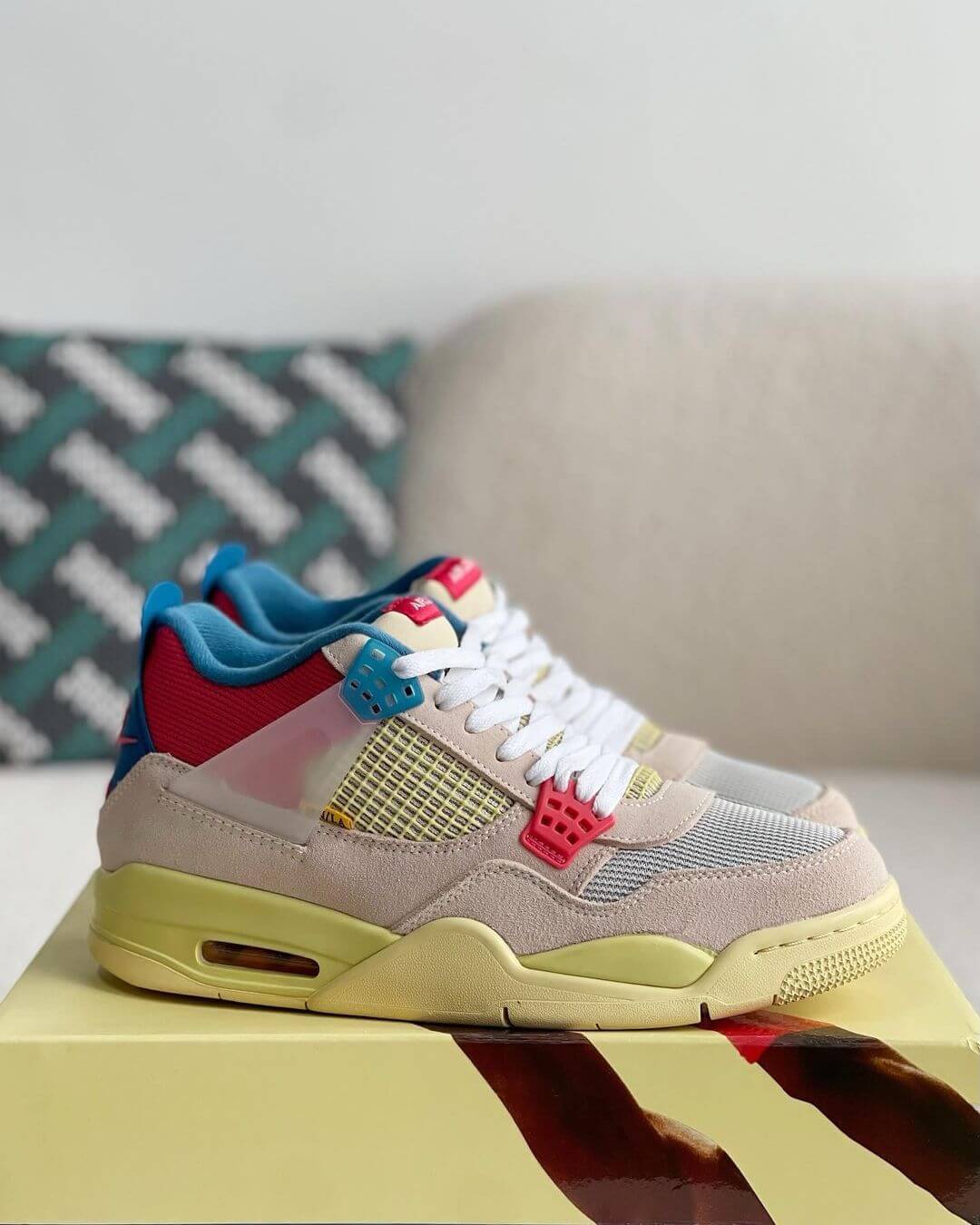 Union LA x Air Jordan 4 'Guava Ice' sneakers with a beige suede upper, vibrant pink, blue, and yellow accents, and vintage-inspired yellow midsole