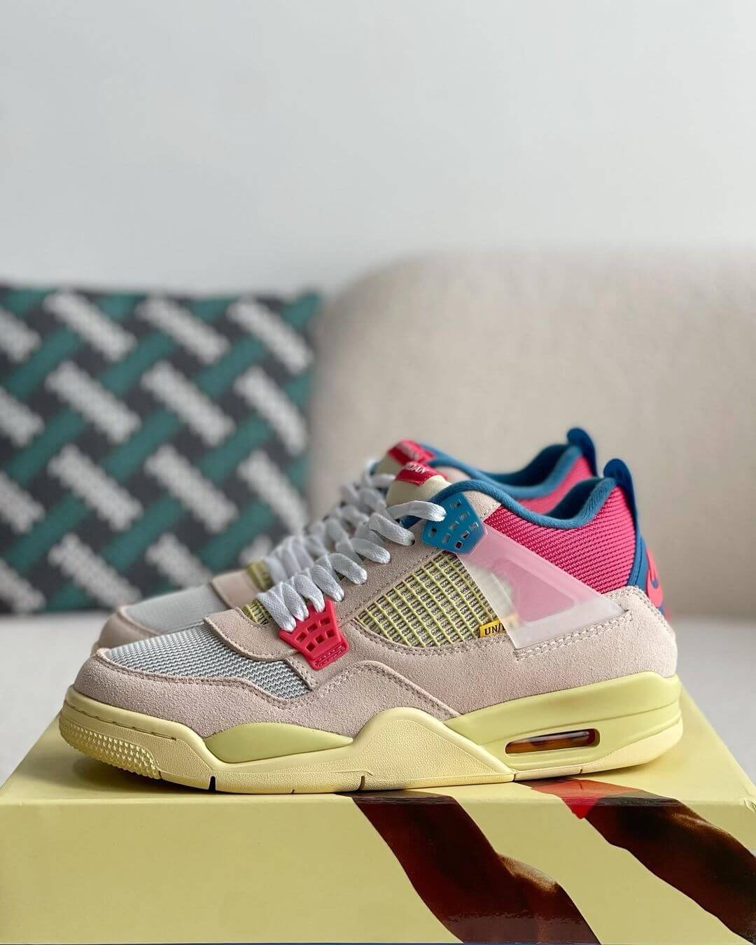 Union LA x Air Jordan 4 'Guava Ice' sneakers with a beige suede upper, vibrant pink, blue, and yellow accents, and vintage-inspired yellow midsole