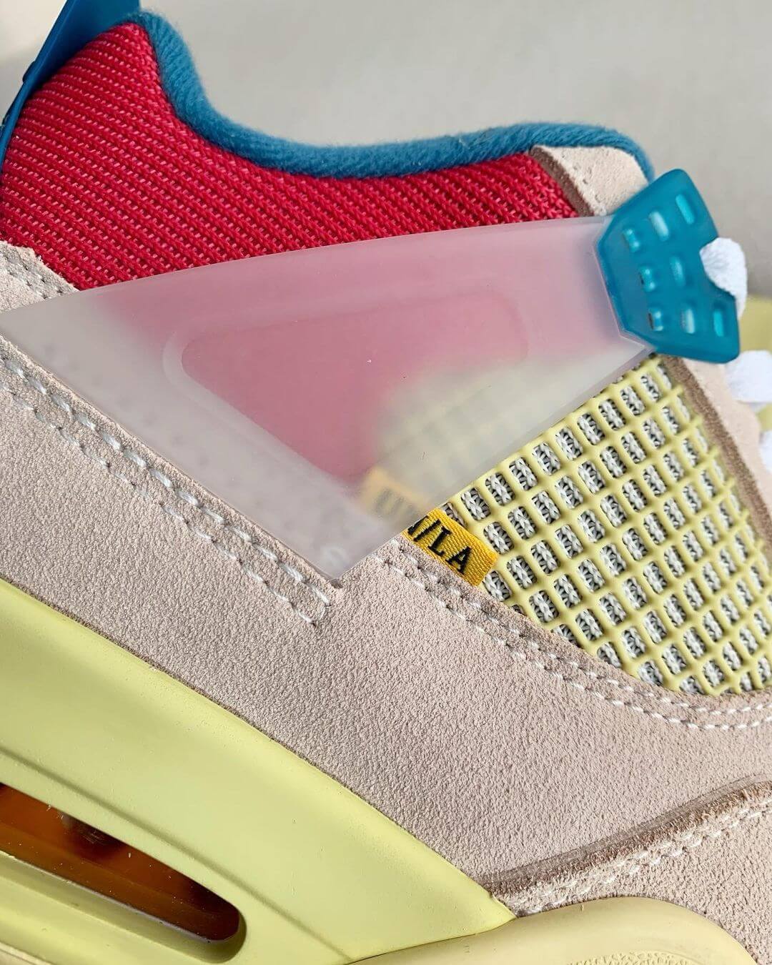 Union LA x Air Jordan 4 'Guava Ice' sneakers with a beige suede upper, vibrant pink, blue, and yellow accents, and vintage-inspired yellow midsole