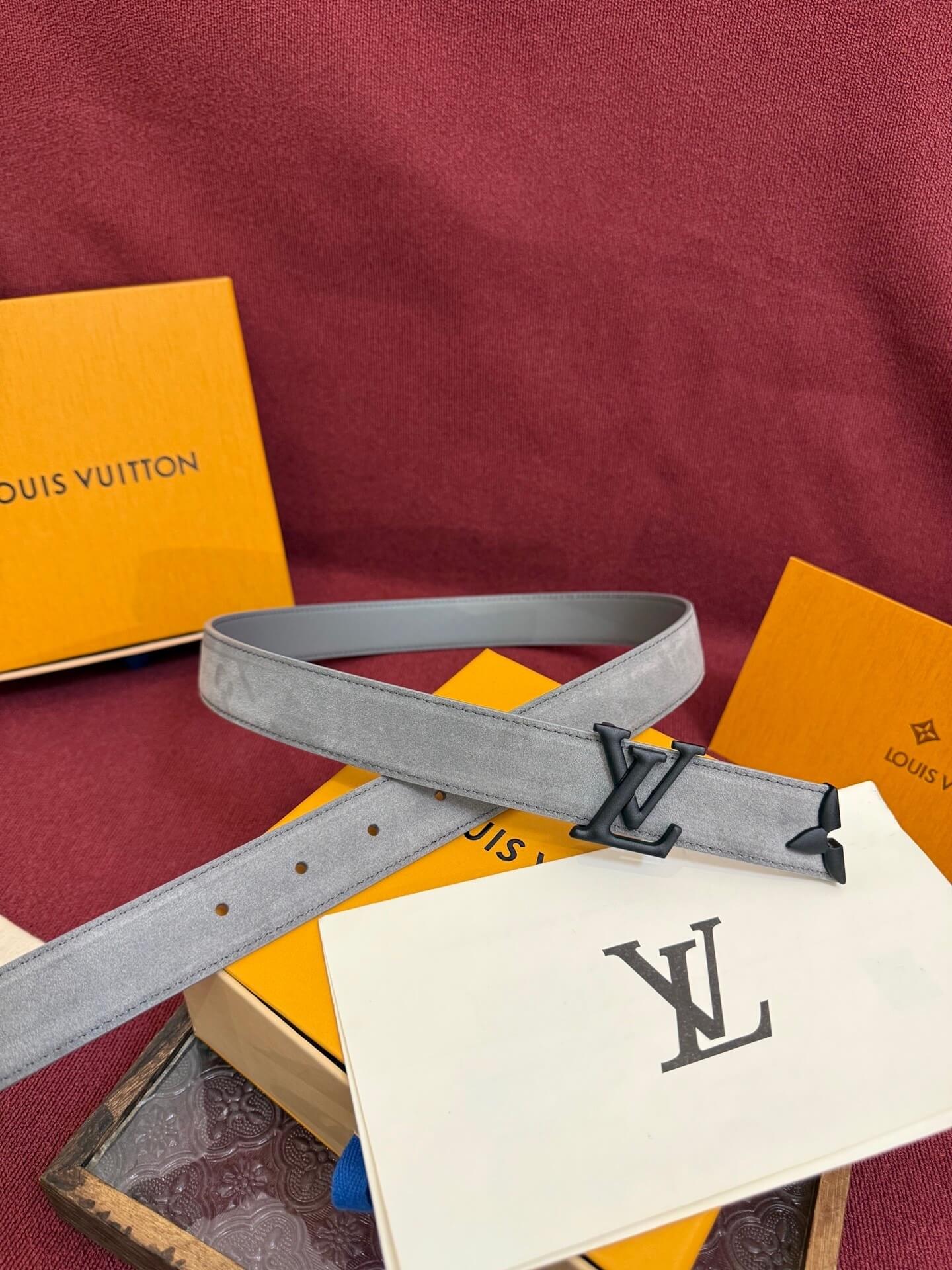 Louis Vuitton belt with logo on a red surface with brand packaging.