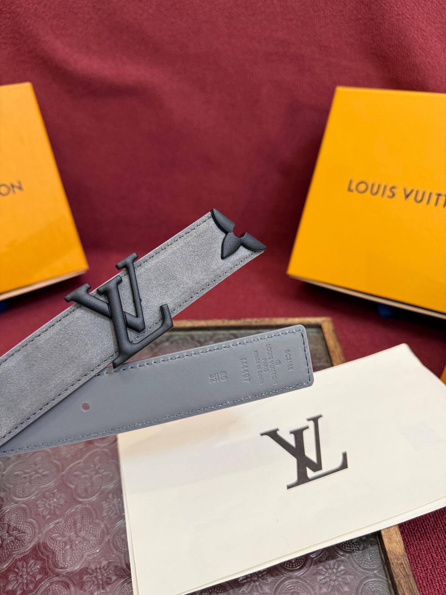 Louis Vuitton belt and accessories on a red surface with branded boxes.