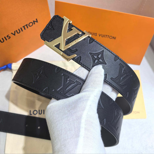 Louis Vuitton belt with gold buckle on a white surface with an orange Louis Vuitton box in the background.