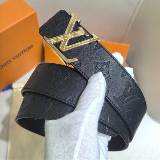Black Louis Vuitton belt with gold buckle held by a gloved hand, with an orange box in the background.